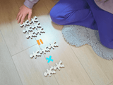 Owloo Master Buddies wooden balancing toy with a child building shapes on the floor