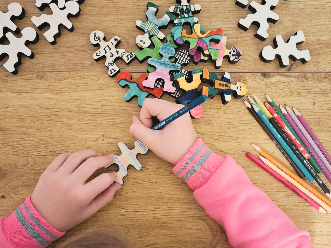 Owloo Master Buddies wooden balancing toy with a child coloring and decorating wooden figures using colored pencils