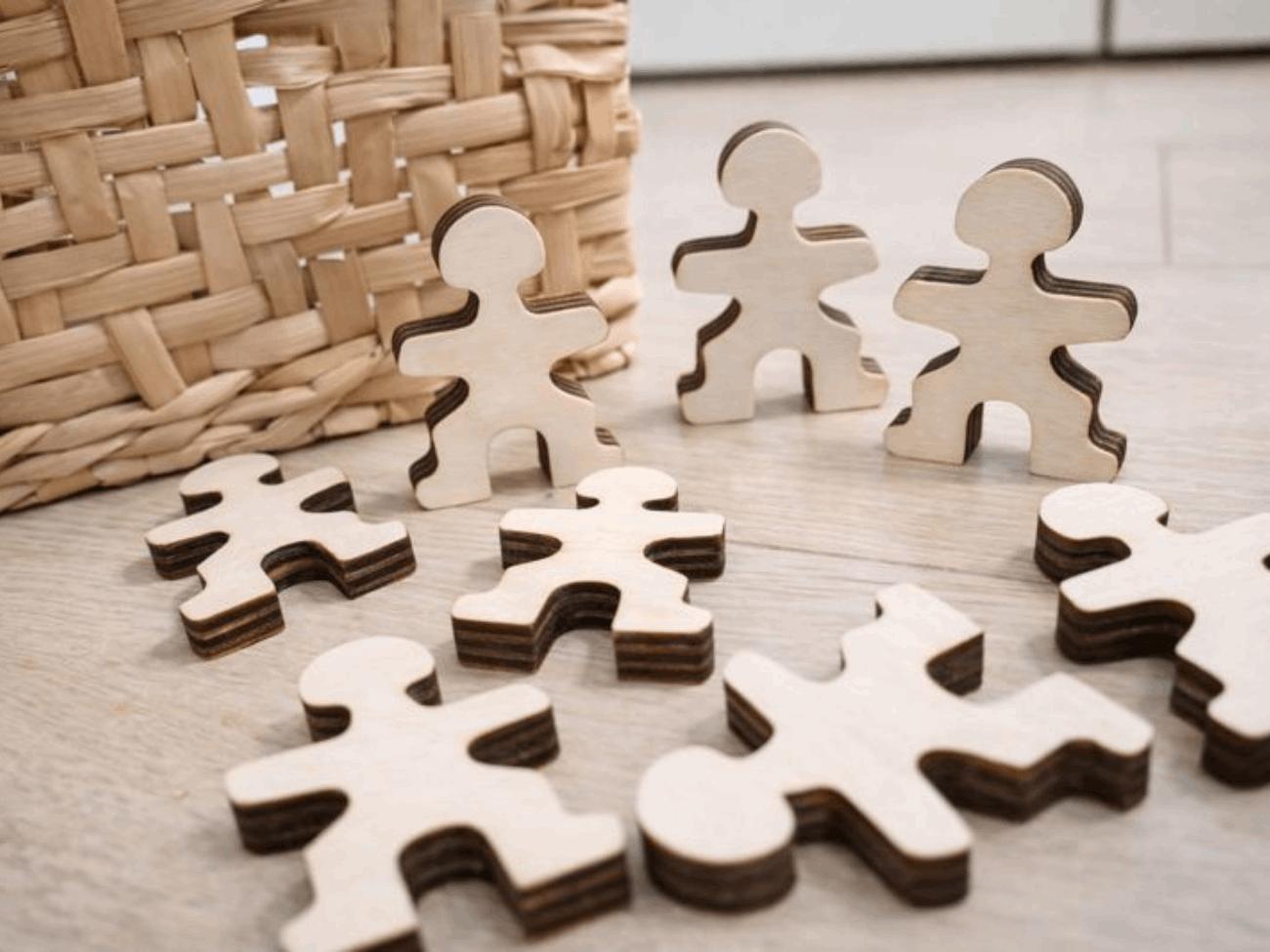 Wooden Master Buddies figures scattered and standing upright on the floor, inviting open-ended balance and construction play in a natural home setting